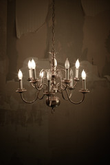 Old Broken Brass Chandelier in an Abandoned House with the Wall Paper peeling off the walls