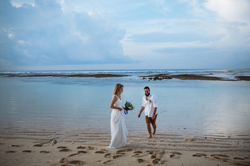 couple in love - bride and groom with a blue bouquet on the wedding day hug and kiss on the beach by the blue ocean on the exotic Asian island of Bali in Indonesia