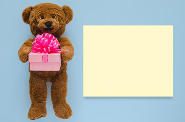 Teddy bear with mustache holding gift box with empty yellow space for text on blue background. Father day concept.