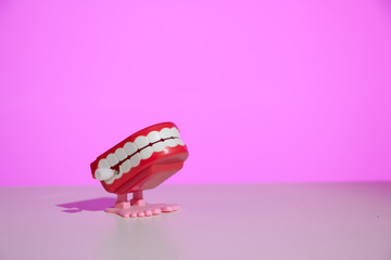 Classic chattering teeth wind-up toy on a modern pink background with copy space.