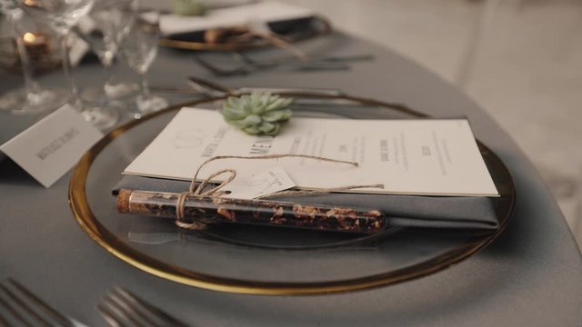 Top view of table serving with green decorative element and cutlery in the fashionable luxury restaurant, tablets with guest names and menu