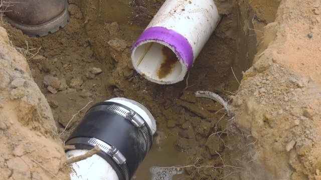 Close up of pvc pipe leaking raw sewage into the ground