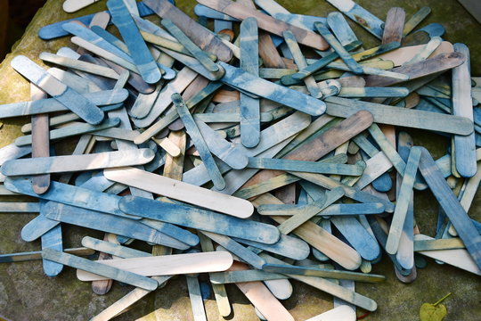 There are many ice cream sticks lined up on the table. Ice cream sticks are dirty because they are dyed in blue so that the children learn to do tie-dyeing activities in the hobby club for the holiday