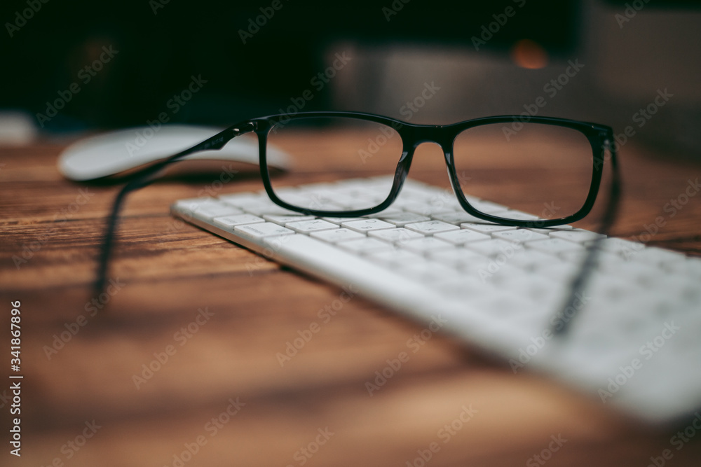 Wall mural Glasses for sight and vision correction and protection from computer on the wooden table on the keyboard