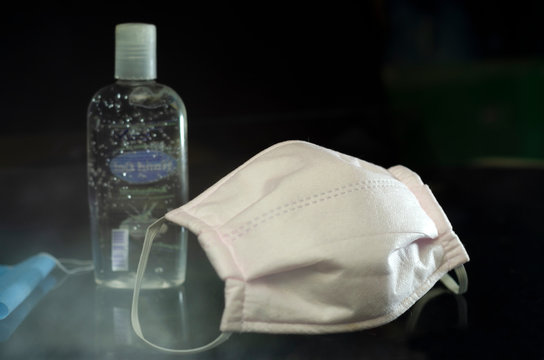 Cubrebocas de tela blanco con gel antibacterial en fondo negro