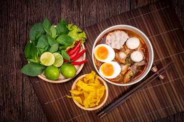 Spicy Noodles with Egg, fish ball and minced pork, Spicy Pork noodle with Spicy soup on wood background.