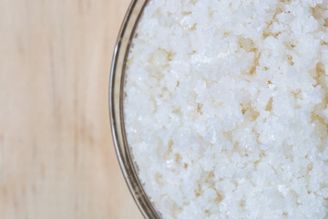 Close up of sea salt in bowl on wooden background, Sea salt is salt that is produced by the evaporation of seawater. Used as a seasoning in foods, cooking, cosmetics and for preserving food..