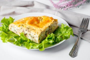 Homemade fish pie with greens on a plate. Mediterranean dish on a white background.