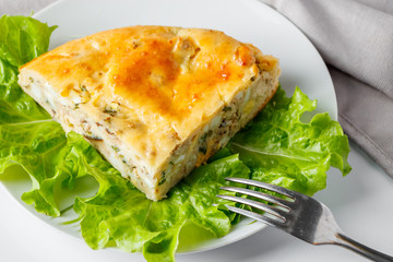 Fish pie on a plate. A piece of cake with mackerel and greens on a white background.