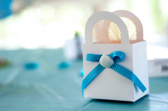 Close-up Of White Bag With Blue Ribbon On Table