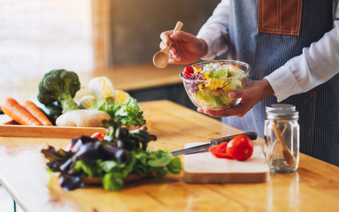 Closeup image of a female chef cooking and holding a bowl of fresh mixed vegetables salad to eat in kitchen