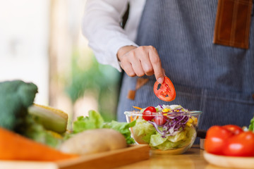 Closeup image of a female chef cooking a fresh mixed vegetables salad in kitchen