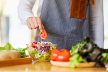Closeup image of a female chef cooking a fresh mixed vegetables salad in kitchen