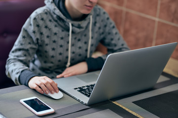 The girl is sitting at home at the computer. A girl in a grey coat. The girl works at home. stay at home. quarantine. covid-19. girl freelancer. wireless mouse. phone. stay at home
