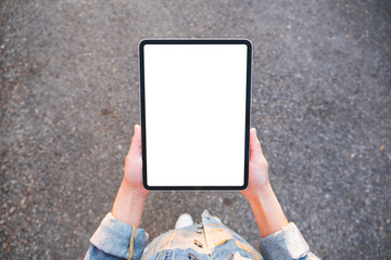 Top view mockup image of hands holding black tablet pc with blank white screen in the outdoors street background © Farknot Architect