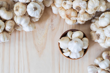 Garlic bulbs in wooden bowl with garlics on wooden table with copy space..