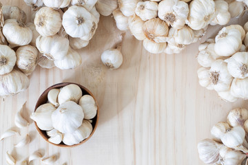 Garlics in wooden bowl with garlics on wooden table with copy space..