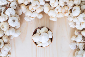 Garlics in wooden bowl with garlics on wooden table