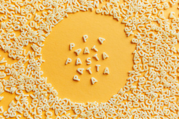 Pasta text of macaroni letters in a round macaroni frame on a yellow background