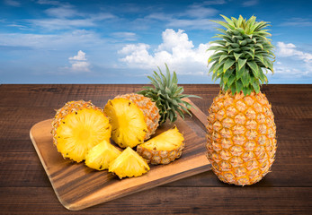Fototapeta na wymiar Fresh Pineapple on the brown wooden table in sea background, Fresh Pineapple fruit. Pineapple fresh fruit on wooden table in blur beach background