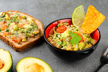 Guacamole with wholemeal bread on gray stone background. Fast food.