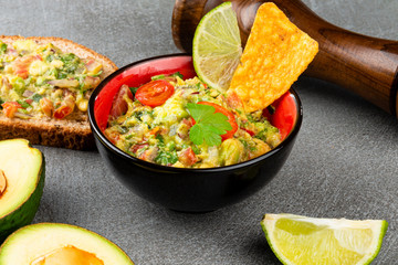 Traditional mexican homemade guacamole sauce in a black and red bowl. Typical mexican food.