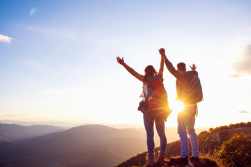 happy couple man and woman tourist at top of mountain at sunset outdoors during a hike in summer