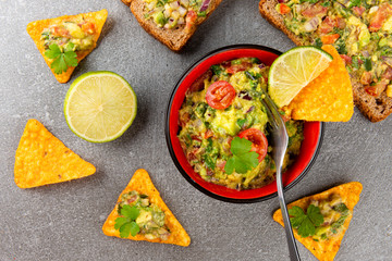 Bowl of fresh Guacamole with nachos chips and herbs. Typical mexican food.