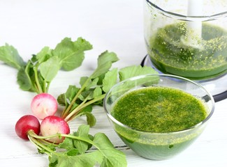 Mixed organic radish leaves with sunflower seeds. Healthy and cheap smoothie in a bowl on white wooden table.