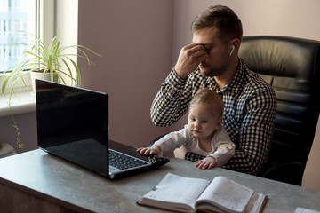 Young sad depressed working father work at home office while babysitting his playful baby daughter at home.Negative emotion concept