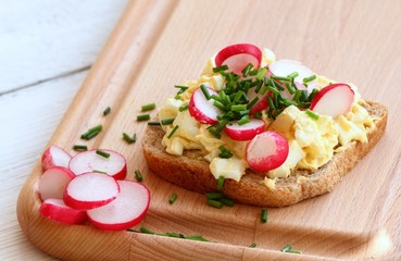 Egg salad over whole grain toast with radish and chives.  Homemade spread made from eggs and processed cheese on the table.