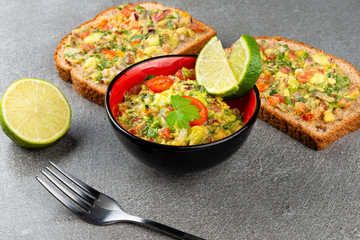 Black and red Bowl with fresh Guacamole with wholemeal bread. Typical mexican food