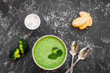Obraz na płótnie Canvas Broccoli cream soup, bread, spoon on grey kitchen desk top-down