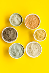 cosmetic clay - Yellow, red, white, blue and black dry powder - top-down flat lay on yellow table