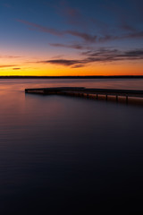 Obraz premium Sunset on the shore of the lake with a footbridge