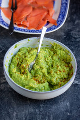 Avocado smash sauce in bowl on marble table, healthy eating food concept