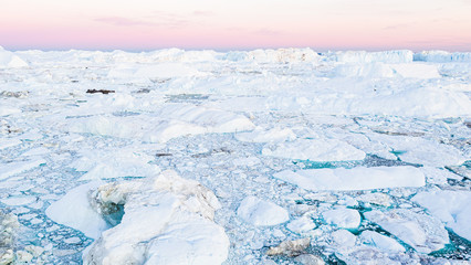 Coronavirus and covid-19 crisis causing less greenhouse gas emissions affecting global warming and climate change. Icebergs in Ilulissat icefjord. Affected by climate change and global warming.
