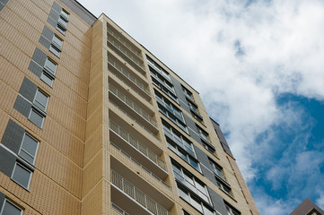 part of the building with Windows and balconies against a blue sky with clouds