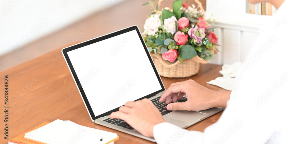 Poster cropped image of smart man's hands typing on computer laptop with white blank screen that putting on