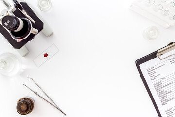 Microscope medical reserch. Hand holds blood sample. White table top-down copy space