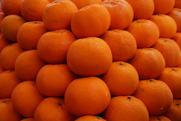 Pile of fresh oranges on market stall.