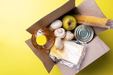 Food donation in a box on a yellow background. Copy of the space.