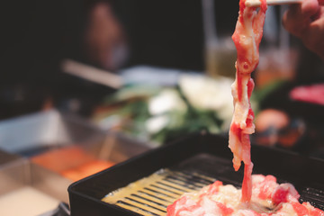 Hand use chopsticks fresh raw meat cooking or Sukiyaki