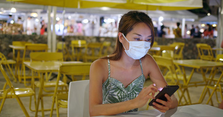 Woman wearing face mask with cellphone at outdoor night market