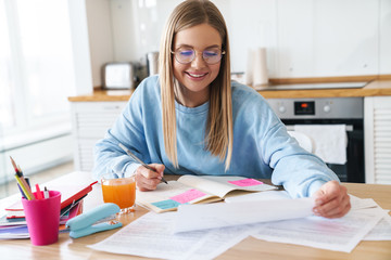 Image of pleased woman smiling while studying with exercise books