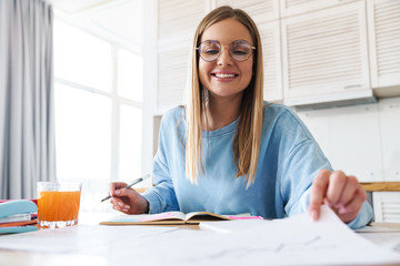 Image of pleased woman smiling while studying with exercise books