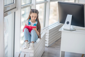 Long-haired girl in white tshirt looking concentrated