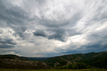 small mountains, illuminated by the setting sun, and storm clouds in the sky