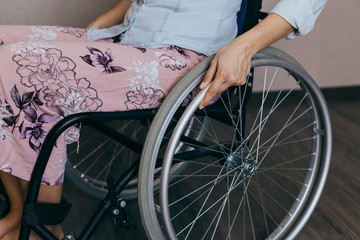Unrecognizable disabled woman in wheelchair at home. Recovery and healthcare concepts.
