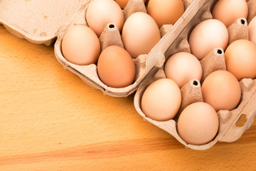 brown chicken eggs in an open cardboard box with eggs on a wooden table. Natural healthy food.